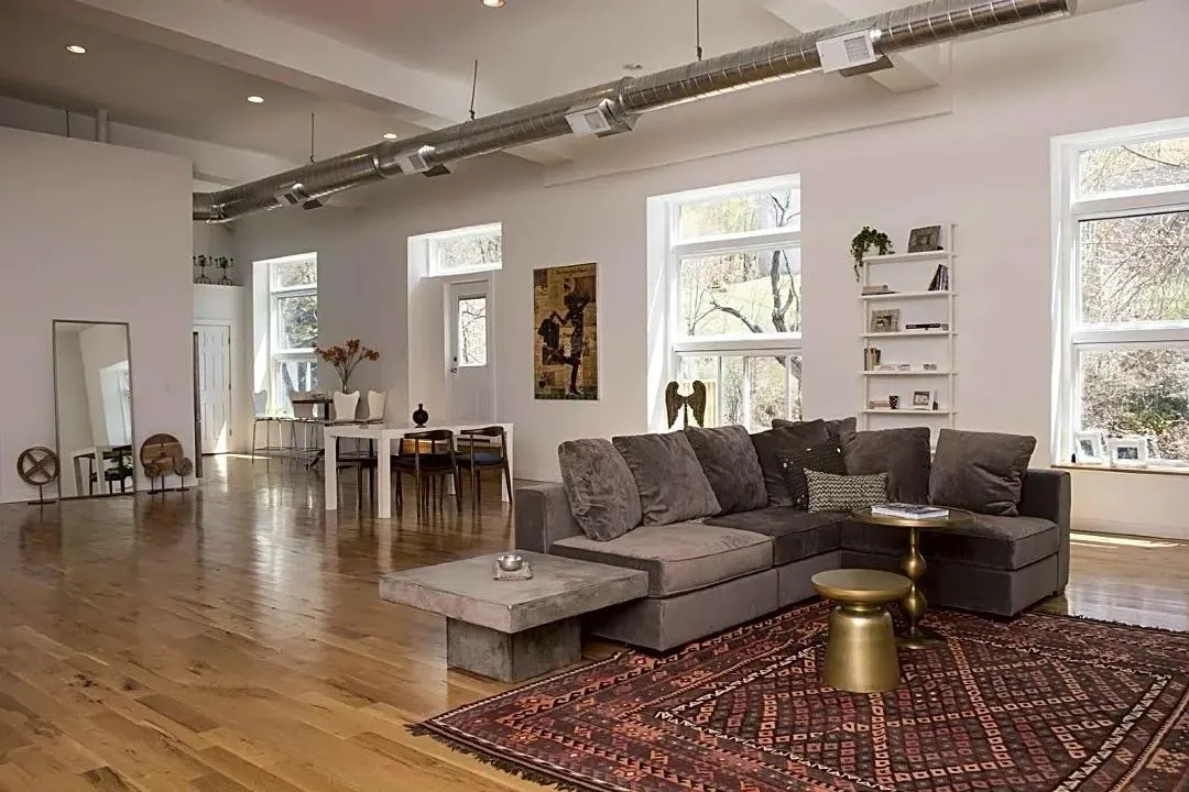 Open-plan living room with wood floors and exposed brick