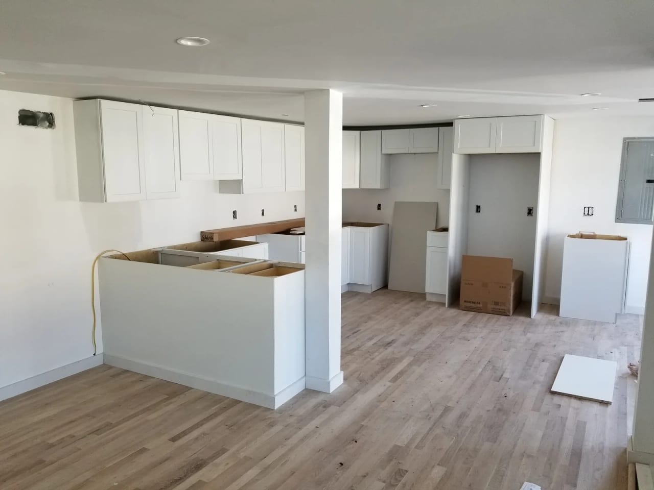 White kitchen cabinets during installation with unfinished counter and appliance areas