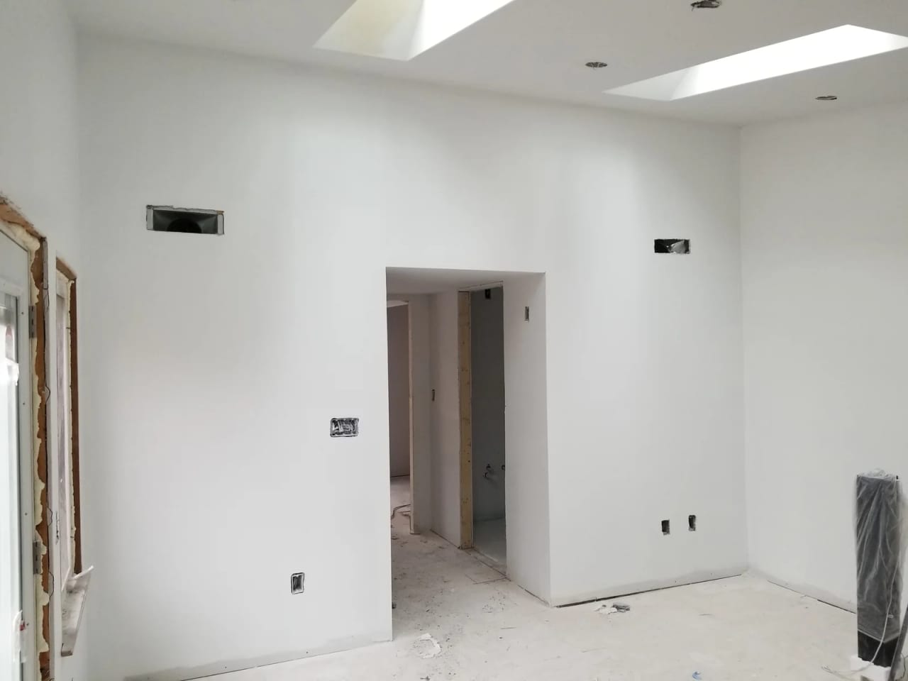 Room during finish work with painted walls, a skylight, and open wall areas