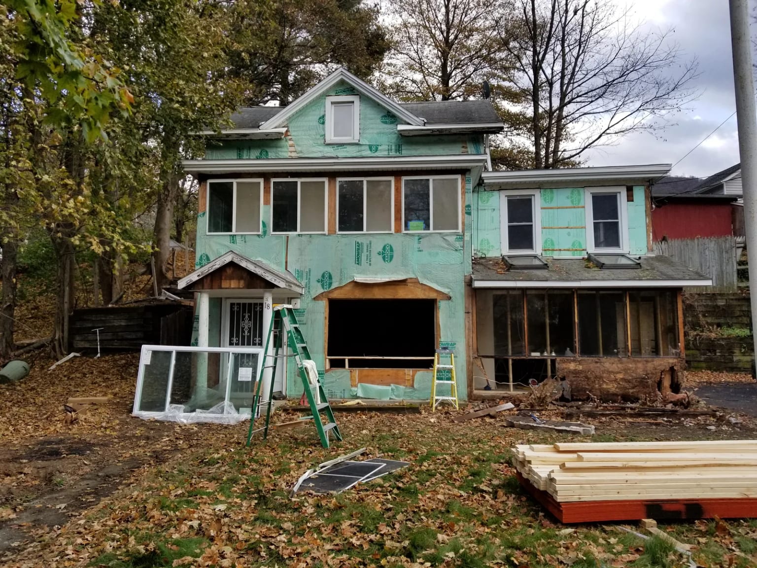 Front exterior with building wrap, removed lower cladding, and opened framing