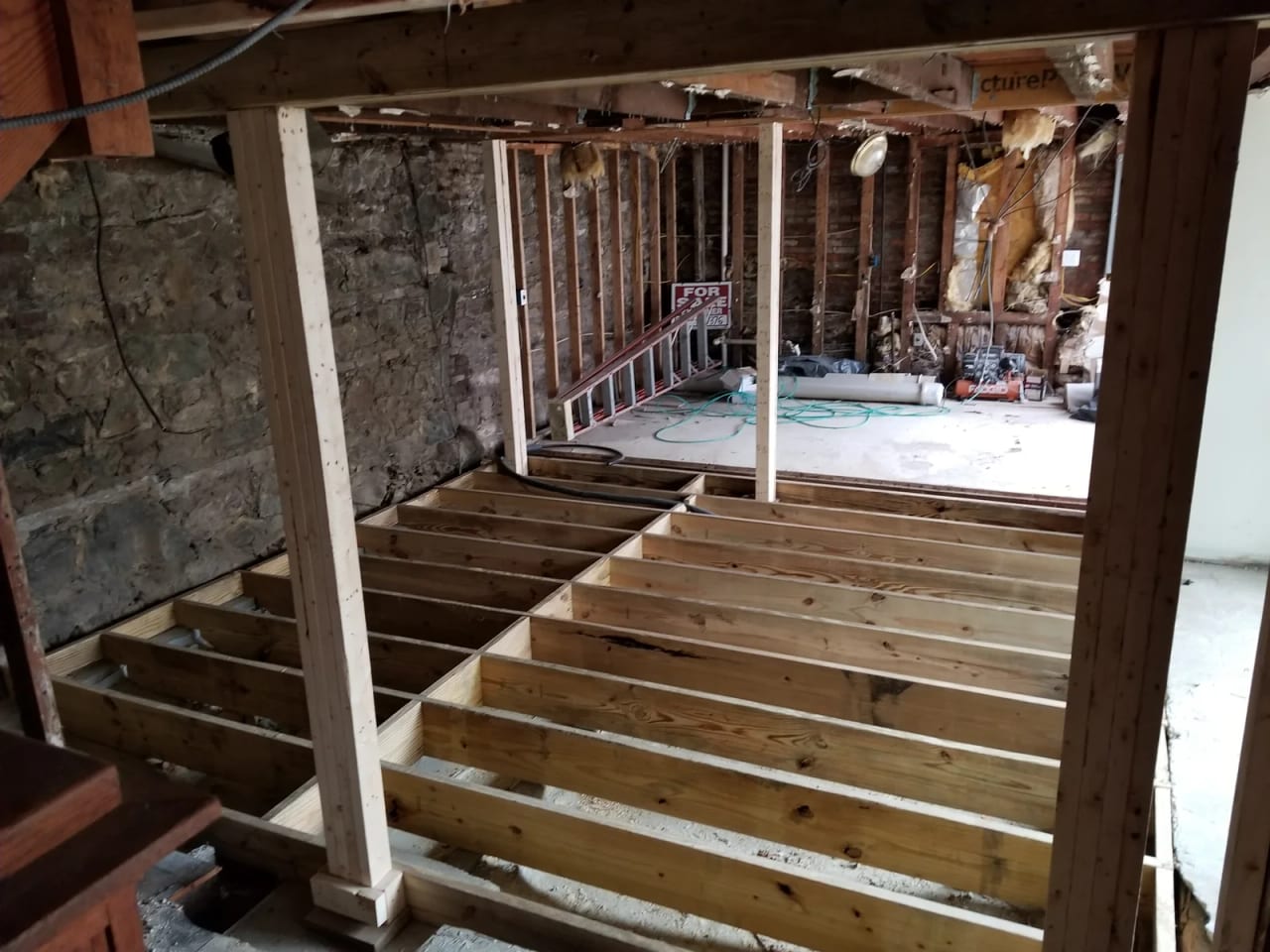 New wood first-floor joists beside the exposed stone foundation wall