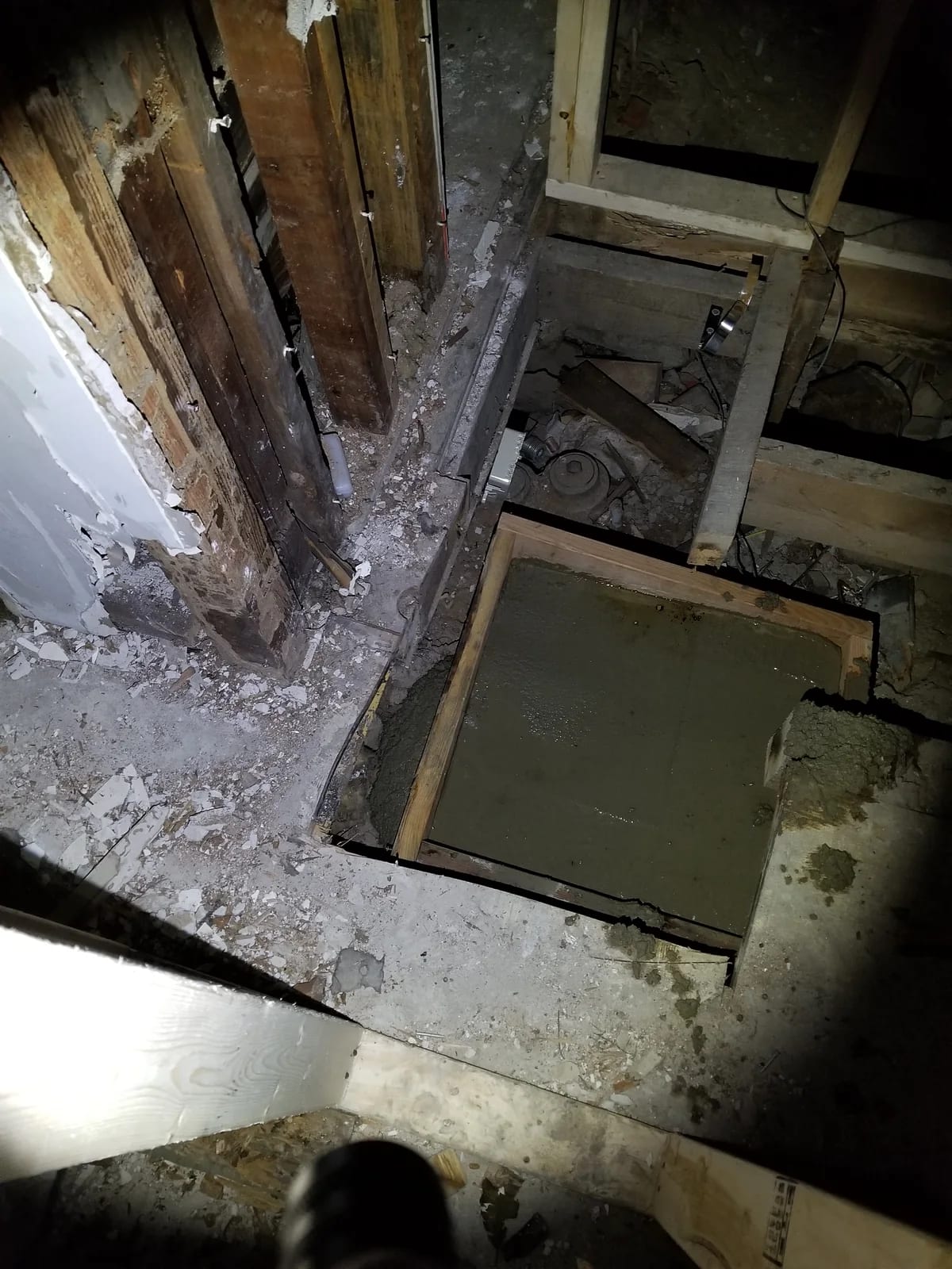 Concrete footing form beneath the opened first floor beside exposed framing