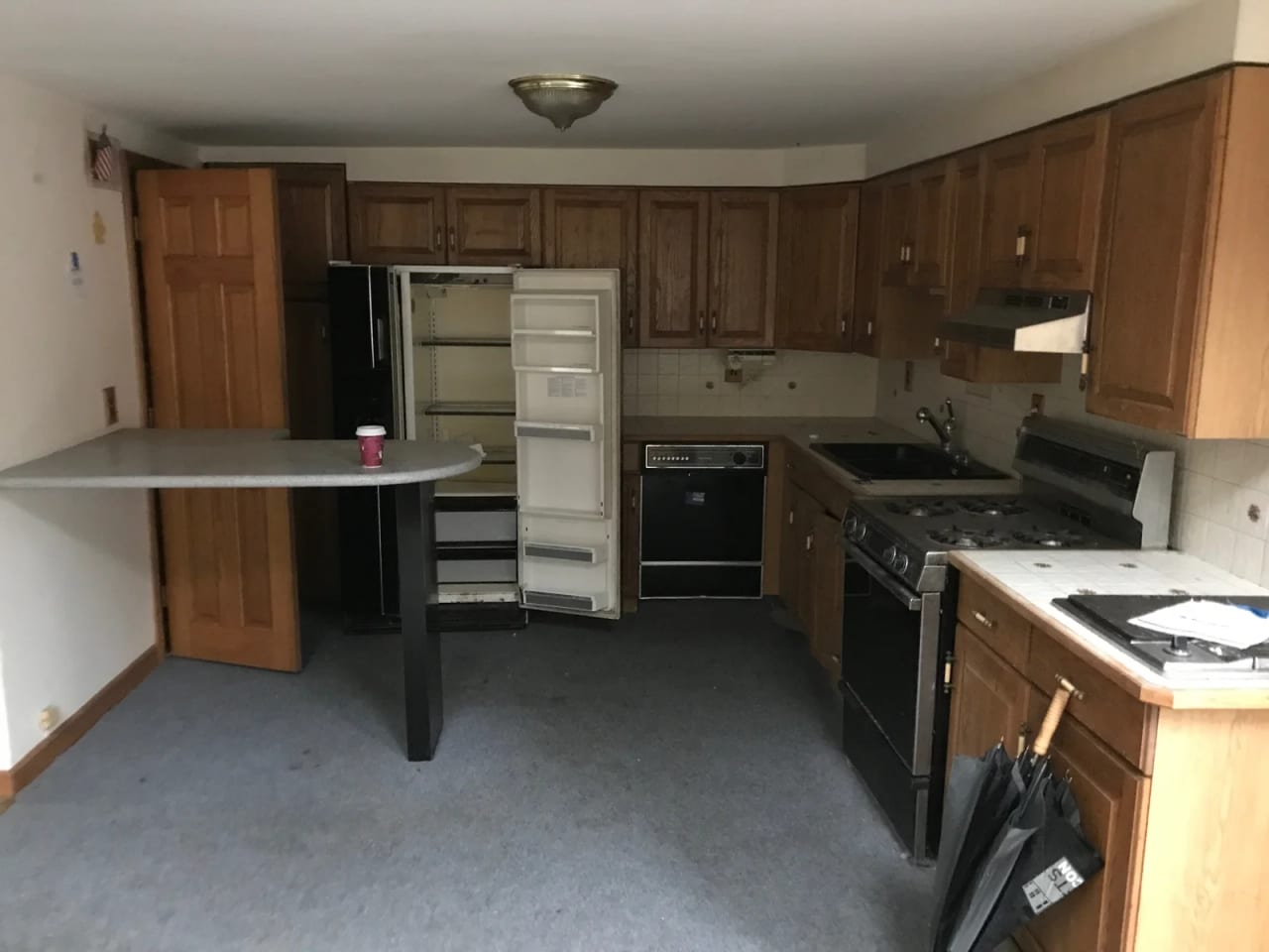 Original kitchen with wood-front cabinets, a peninsula, appliances, and surrounding walls