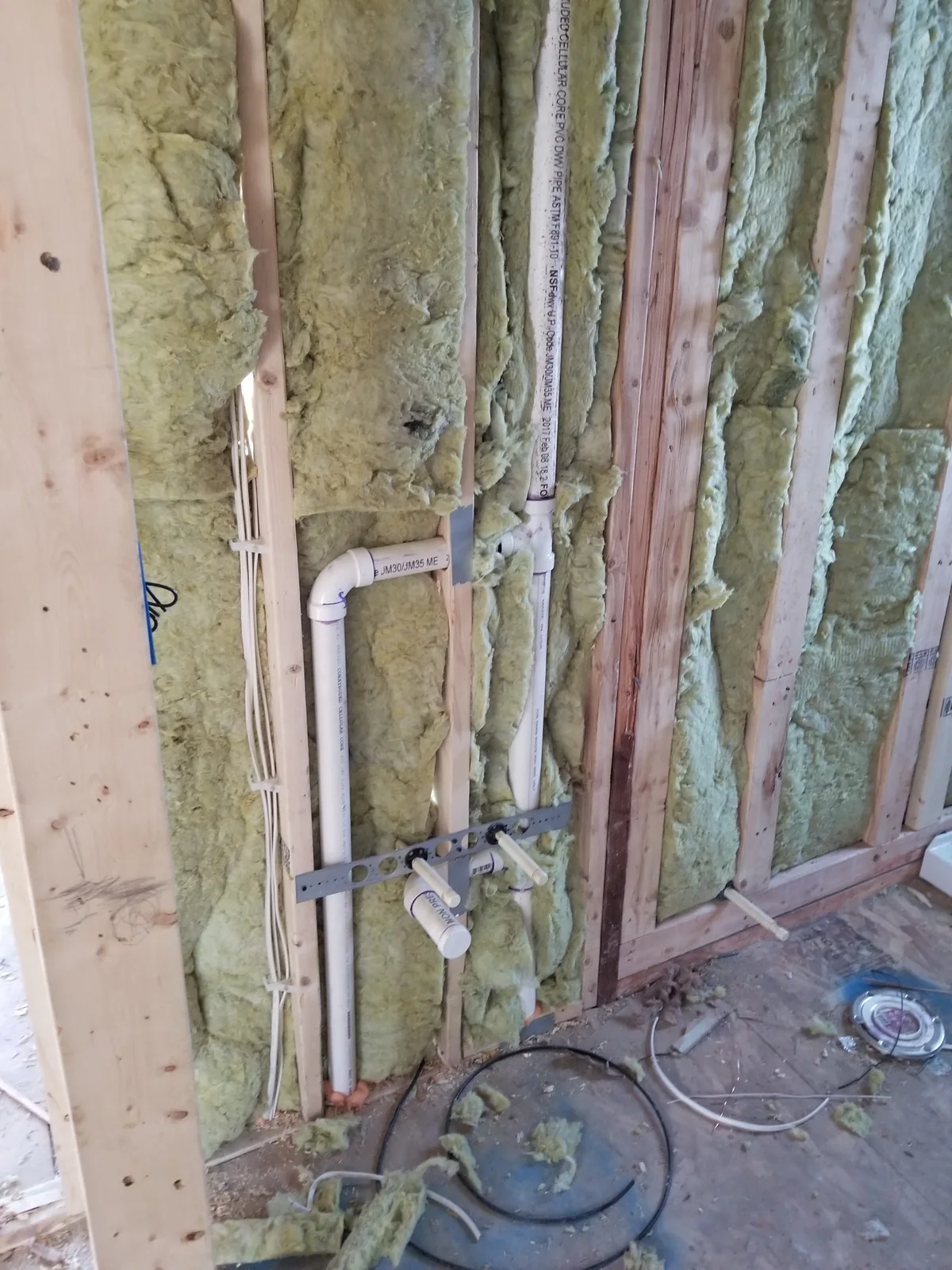 Plumbing piping in an open wall alongside insulation