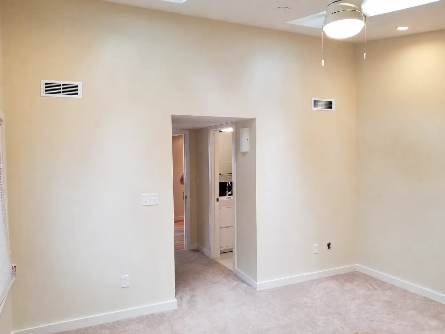 Bedroom with skylights, light carpet, and white wall vent covers