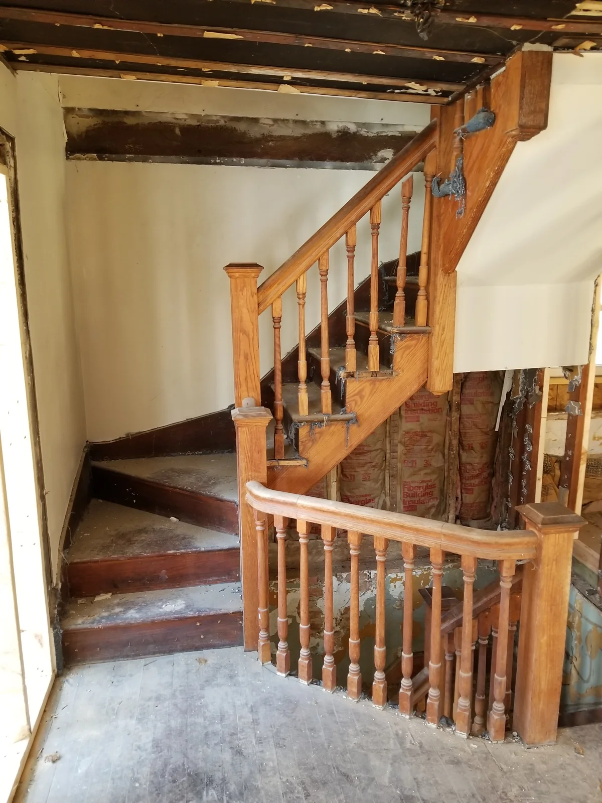 Existing wood staircase beside exposed wall framing during interior work